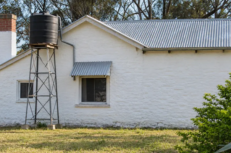 Casa de campo con tanque de agua sobre una torre metálica